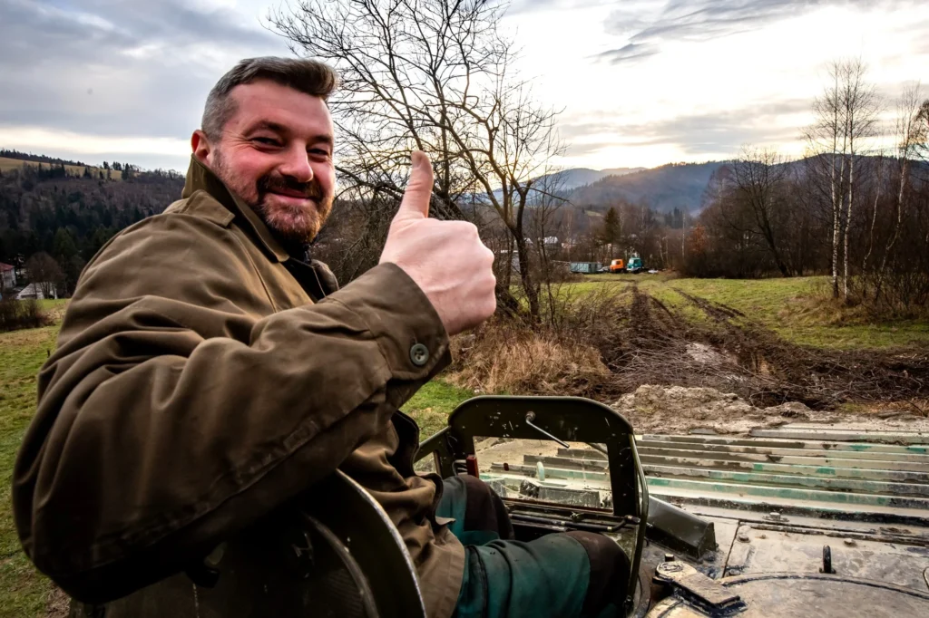 Inštruktor na vozidle s vztýčeným palcom, v pozadí kysucké kopce